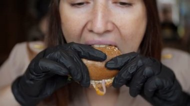 Güzel kızın siyah eldiven kafede hamburger yeme yakın çekim