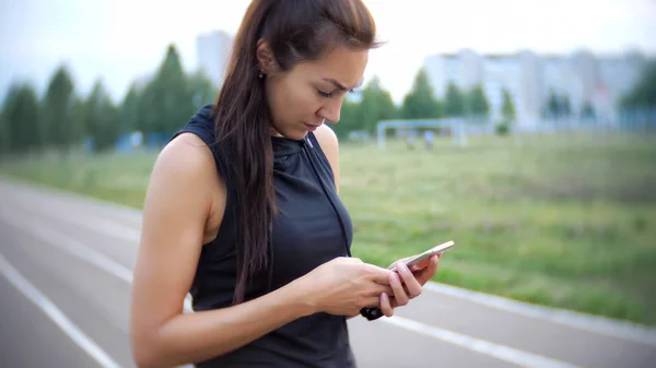 Fiatal lány használni app, sport, és tartsa őt telefonon — Stock Fotó