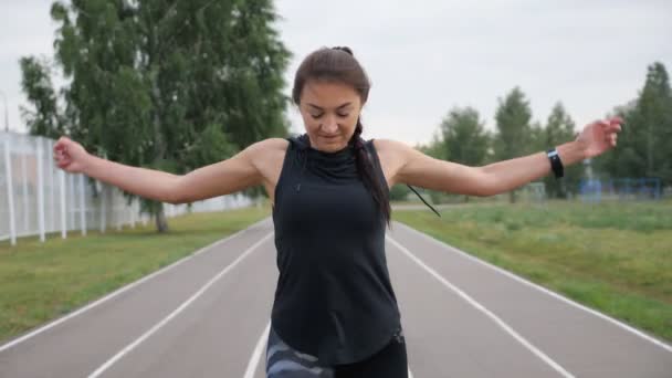 Sportliches Mädchen streckt Arme auf dem Laufband des Stadions aus — Stockvideo