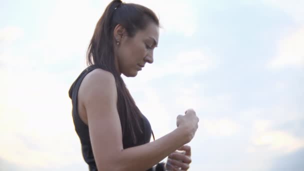 Молодая красивая спортсменка пьет воду из бутылки на открытом воздухе — стоковое видео