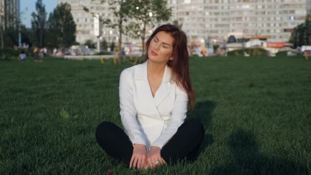 Jovem empresária de terno branco sentado e meditando ao ar livre — Vídeo de Stock