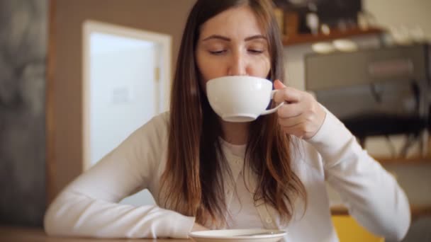 Mooie vrouw in een café koffie drinken — Stockvideo