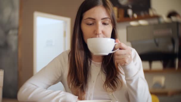 Pretty woman in a cafe drinking coffee — Stock Video
