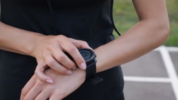 Frau beim Aufbau der Fitness-Smartwatch zum Laufen. sportliches Mädchen überprüft Uhrengerät, Nahaufnahme — Stockvideo