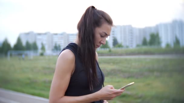 Menina jovem usar aplicativo esporte e segurar seu telefone — Vídeo de Stock