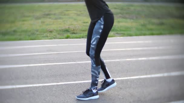 Спортивная девушка делает упражнения на ногах на открытом стадионе — стоковое видео