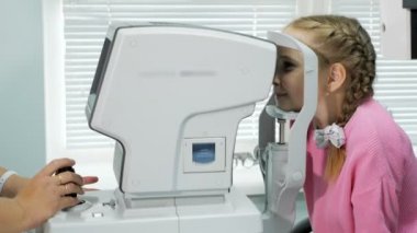 Bir kadın doktor Refraktometre makine ile çalışma kapatın. Küçük bir kız gözlerini test yaptırıyor