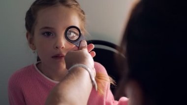 Optometri kavramı - küçük kız inceleyerek büyüteç ile tıp doktoru