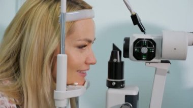 Gözlükçü dükkanda test cihazı ile ölçülen gözlere sahip kadın