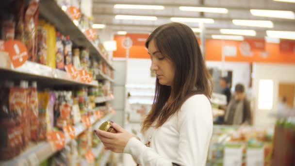 Mujer joven parada en una botella de ketchup en manos de un supermercado — Vídeos de Stock