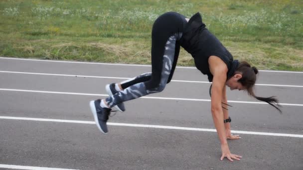 Sportowy dziewczyna robi ćwiczenia push-up, skok i klaskanie odkryty na stadionie — Wideo stockowe