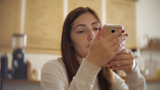Κορίτσι έλεγχο το τηλέφωνό της, ενώ έχοντας ένα φλιτζάνι του καφέ — Αρχείο Βίντεο