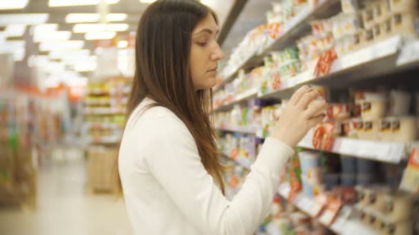 Mooie vrouw winkelen voor zuivelproducten bij een supermarkt — Stockvideo