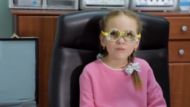 Little girl in a eye test glasses in clinic — Stock Video