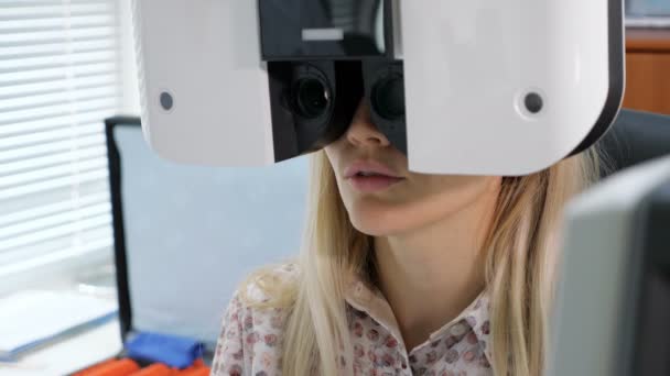 Young woman looking at refractometer eye test machine in ophthalmology — Stock Video