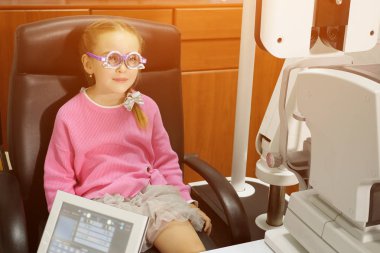 genç kız, gözlükçü, optometrist veya göz doktoru tarafından gerçekleştirilen göz muayenesi geçiriyor.