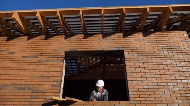 Człowiek w okienku budowy domu — Wideo stockowe