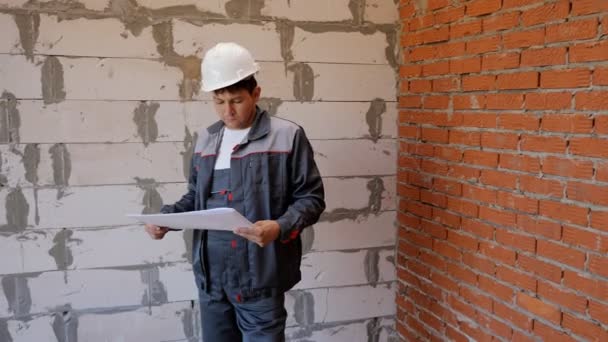 Construtor com plantas de papel em sala vazia — Vídeo de Stock