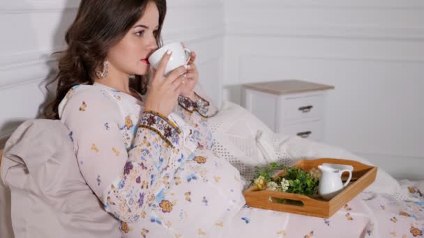 Relaxing pregnant woman drinking healthy tea in bed — Stock Video