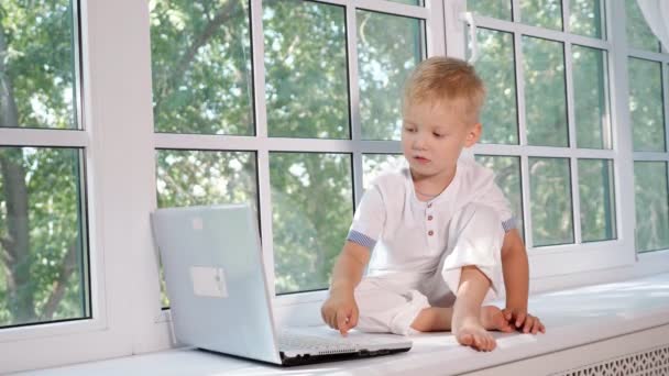 Menino com laptop na soleira da janela — Vídeo de Stock