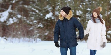 Genç erkek ve kadın el ele tutuşarak ve güzel kış ormanda yürüyüş dış giyim