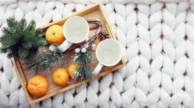 Festival süsleri, mandalina, çam kozalakları, köknar ağacı, çam dalları ile iki beyaz bardak üstten görünüm ahşap tahta üzerinde