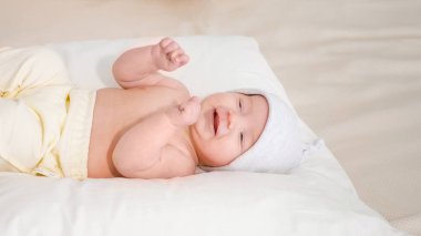 gülümseyen bebek şapkalı beyaz yumuşak yatağa evde yatarken