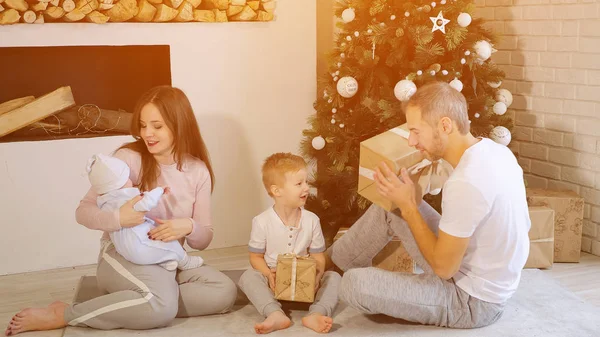 Familia abriendo regalos de Navidad cerca del árbol — Foto de Stock