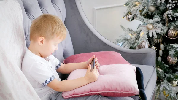 Niño jugando juegos de teléfonos inteligentes en el sofá — Foto de Stock