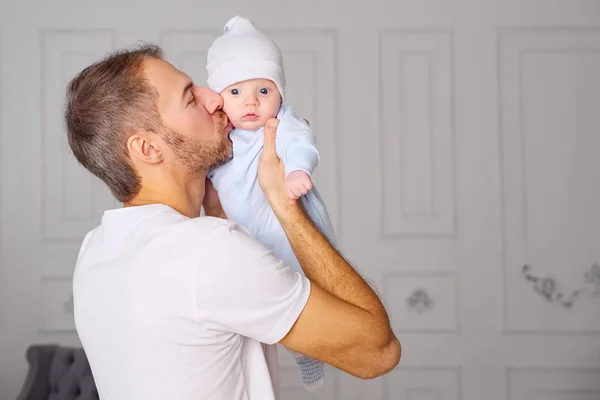 Vue latérale du bel homme embrassant bébé tout en restant debout dans une chambre élégante à la maison — Photo