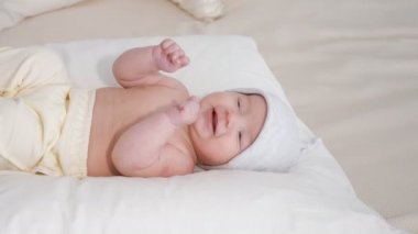 gülümseyen bebek şapkalı beyaz yumuşak yatağa evde yatarken