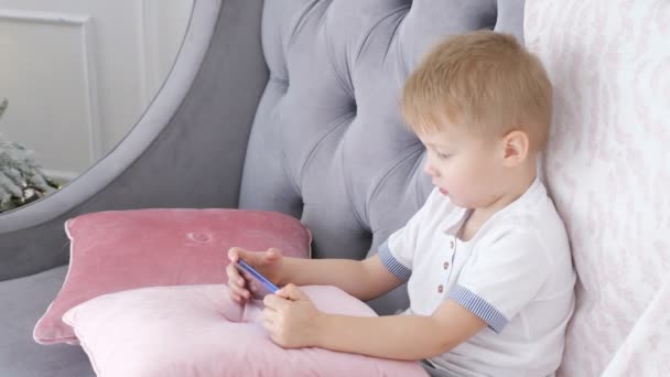 Junge spielt Smartphone-Spiele auf Sofa — Stockvideo
