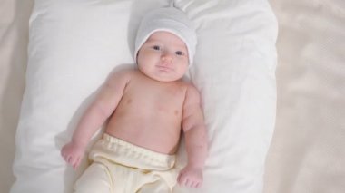 Tatlı bebek şapka ve gri arka plan üzerinde yalan sırasında kameraya bakarak pantolon atış yukarıdan