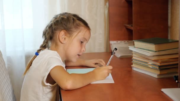 Сконцентрированная девочка делает домашнее задание — стоковое видео