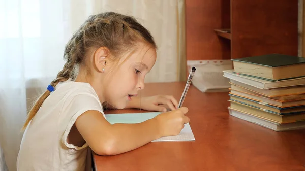 Chica concentrada haciendo tarea escolar —  Fotos de Stock