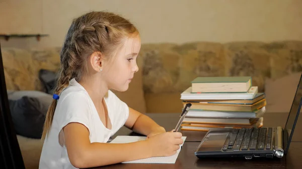 Маленькая девочка делает домашнее задание с ноутбуком — стоковое фото