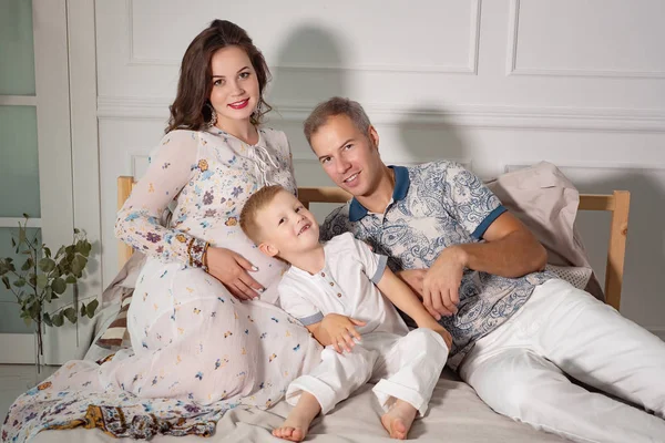 Mujer embarazada feliz con la familia en la cama — Foto de Stock