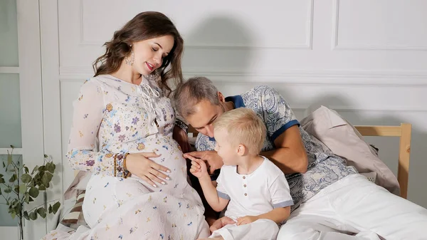 Szczęśliwa Kobieta w ciąży z rodziną na łóżku — Zdjęcie stockowe