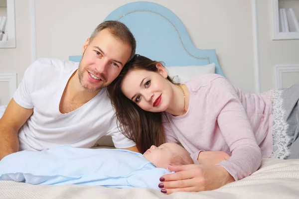 Parents heureux tout en étant couché sur un lit doux près bébé endormi doux dans une chambre élégante — Photo