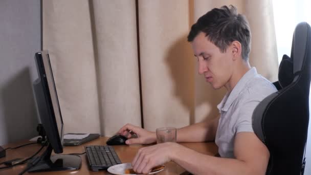 Чоловік вдома їсть піцу і грає на комп'ютері — стокове відео