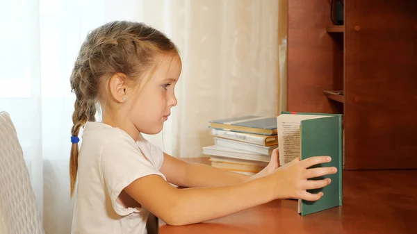 Menina estudando em livro de leitura de mesa — Fotografia de Stock