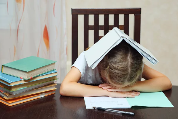 Müde Schülerin mit Büchern am Tisch — Stockfoto