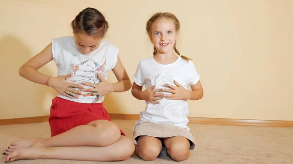 Little sisters sitter på golvet och måla en t-shirt med sina händer — Stockfoto