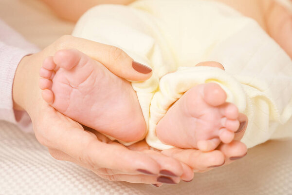 Рука спящего младенца в руке матери рядом на кровати
