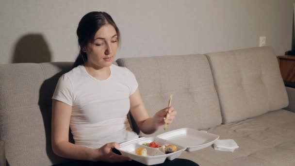 Женщина ест японские роллы и суши дома — стоковое видео