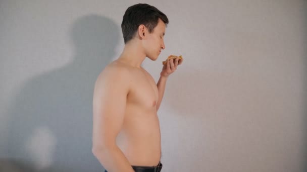 Genç adam bir dilim pizza gri arka plan üzerinde kokulu — Stok video