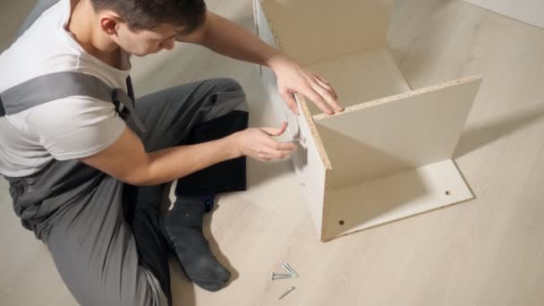 Young repairman assembling new table at home interior — Stock Video