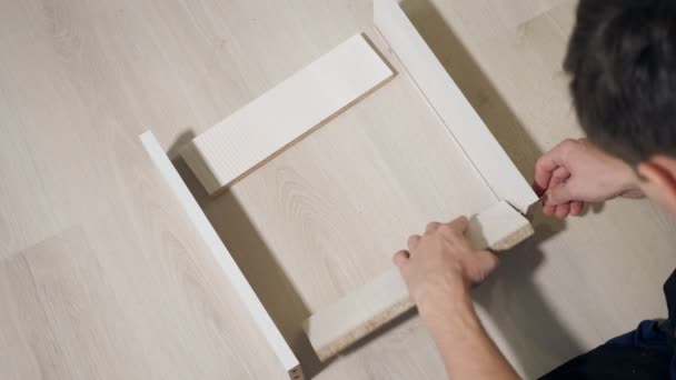 Молодой ремонтник собирает новый стол в интерьере дома — стоковое видео