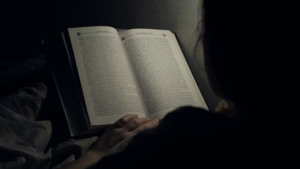 Young woman reading book in bed at night home — Stock Video