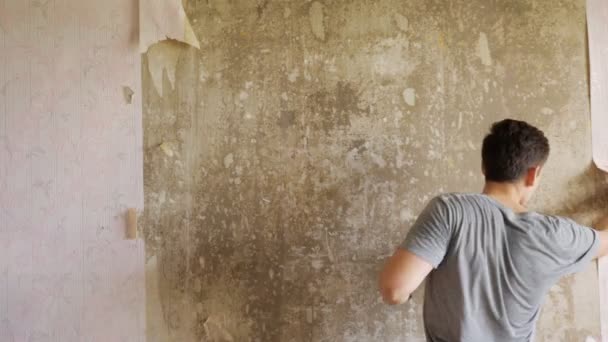 Homem arrancando papel de parede no quarto — Vídeo de Stock